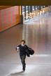 Male student in school uniform running with trophy in school corridor