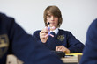 Portrait of male student in school uniform holding atom model at desk in classroom