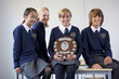 Portrait of smiling students in school uniforms holding award plaque