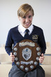 Portrait of smiling female student in school uniform holding award plaque