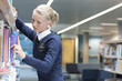 Female student in school uniform choosing book from shelf in school library