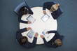 Students in school uniforms using digital tablets at round table