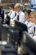 Students in school uniforms sitting at computers in library