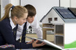 Photo: Students in school uniforms examining energy efficient house model in science class Students in school uniforms examining energy efficient house model in science class
