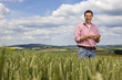Portrait of smiling farmer standing in young wheat field