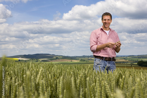Photo: Portrait of smiling farmer standing in young wheat field Portrait of smiling farmer standing in young wheat field