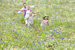 Family running with arms outstretched in wildflower field