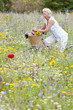 Smiling woman sitting on bicycle in field of wildflowers