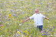 Senior man with arms outstretched enjoying field of wildflowers