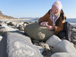 Woman looking at fossil in rock on ocean beach in winter