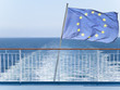 European Union flag on railing of ship with ocean water in background