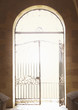 Open ornate iron gate in arched doorway