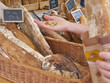 Woman holding coins buying rustic loaf of bread from market