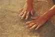 Close up of hands in ocean water at beach