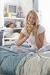 Portrait of smiling young woman in pajamas drinking coffee in bed
