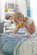 Woman with head in hands sitting on bed with coffee cup