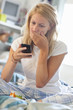 Worried young woman in pajamas reading text message on phone in bed