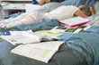 Homework next to young woman in pajamas laying in bed
