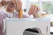 Close up of young woman attaching thread to sewing machine