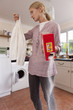 Young woman holding shirt and spilling detergent in laundry room