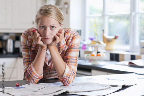 Photo: Portrait of young woman with head in hands surrounded by classified ads Portrait of young woman with head in hands surrounded by classified ads