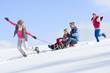 Happy family sledding down snowy hill