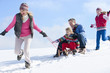 Happy family sledding down snowy hill