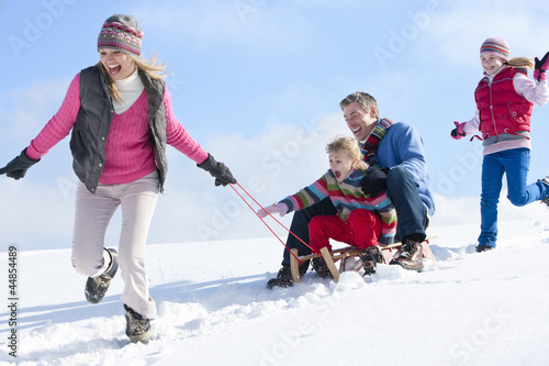 Photo: Happy family sledding down snowy hill Happy family sledding down snowy hill