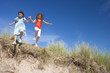 Girls holding hands and jumping on sunny beach
