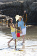 Boy and girl with fishing net and seaweed in tide pool