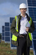 Portrait of smiling engineer standing next to solar panels