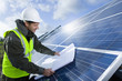 Engineer with blueprint inspecting solar panels