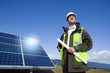 Engineer with blueprint in front of solar panel