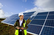 Engineer with digital tablet standing in front of solar panels