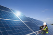 Engineer with digital tablet inspecting solar panels
