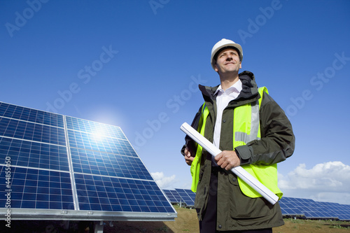 Photo: Engineer with blueprint in front of solar panel Engineer with blueprint in front of solar panel