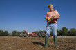 Foto: Portrait of smiling farmer holding potatoes in sunny, rural field with tractors in background Portrait of smiling farmer holding potatoes in sunny, rural field with tractors in background