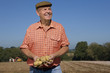 Foto: Smiling farmer holding potatoes in sunny, rural field Smiling farmer holding potatoes in sunny, rural field