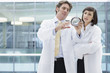 Engineers in lab coats examining part in office