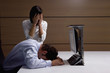 Exhausted businessman and businesswoman at desk in office