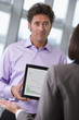 Photo: Businessman showing businesswoman graph on digital tablet Businessman showing businesswoman graph on digital tablet