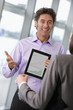 Photo: Businessman showing businesswoman graph on digital tablet Businessman showing businesswoman graph on digital tablet