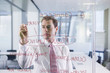 Businessman drawing flow chart on glass window in office