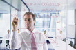 Photo: Businessman drawing graph on glass window in office Businessman drawing graph on glass window in office