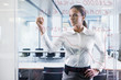 Businesswoman drawing graph on glass window in office