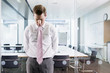Dejected businessman leaning on glass window in conference room