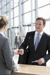 Businessman handing passport to woman at airport counter