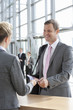 Smiling businessman handing passport to woman at airport counter