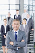 Portrait of confident businessman in suit with business people in background