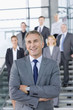Portrait of smiling businessman in suit with business people in background